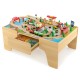 Wooden train set with 84 pieces on a reversible tabletop, featuring a gas station and storage drawer for kids' play.