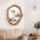 Irregular shaped wall mirror with a natural wood frame, perfect for enhancing light in living rooms or bedrooms.