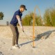 Right-handed golfer using a 56-degree sand wedge in a bunker, showcasing its milled grooves and durable stainless steel.