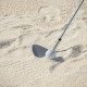 Golf sand wedge with milled grooves and stainless steel head, positioned in sand for improved short game performance.