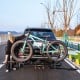 Tilt-able 2-inch hitch mount bike rack holding two bikes, featuring durable metal construction and adjustable wheel.