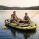 Three-person inflatable fishing raft in green, featuring oars and pump, perfect for lakeside adventures.