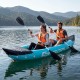 Two people paddling a blue inflatable tandem kayak on a serene lake, featuring heavy-duty construction and aluminum.