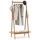 Bamboo clothes rack with hanging rod, rattan shelf, and copper hooks for organized entryway storage.