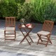 Teak wood tray table with removable top and two folding chairs, perfect for outdoor patio dining and relaxation.