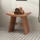 Teak wood shower bench with curved seat, featuring drainage gap and sturdy legs, ideal for bathroom or outdoor use.