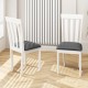 Two white wooden dining chairs with padded black seats, featuring a slat back design, ideal for kitchen or dining room.