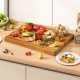 Extra large 24" teak wood cutting board with handle, showcasing vibrant ingredients for versatile kitchen use.