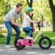 Child riding a pink 12-inch kids bike with training wheels, featuring a dual brake system and ergonomic seat in a park.