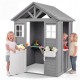 Kids outdoor playhouse in gray spruce wood with sink, featuring a half door and two children playing inside.