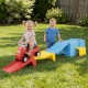 Two toddlers enjoy playing on a multicolor kids ride-on toy with a storage box and downhill race tracks in the backyard.