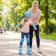 Child learning to skate in blue adjustable roller skates with light-up wheels, supported by an adult in a park.