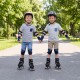 Two children holding hands while roller skating in a park, wearing adjustable black roller skates with light-up wheels.