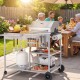 Movable grill table with stainless steel condiment caddies, spacious tabletop, and wheels for easy outdoor BBQ setup.