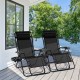 Two black outdoor folding zero gravity reclining lounge chairs with utility tray, perfect for relaxing by the water.