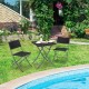 Black folding wicker chairs and table in a patio setting, perfect for outdoor relaxation and space-saving convenience.