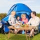 Folding camping table with waterproof surface, set up for a picnic inside a tent, ideal for outdoor activities.