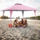 Pop-up gazebo in pink, 13 x 13 ft, providing shade for beach gatherings with sturdy stakes and wind ropes.