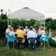 Gray 6.6 x 6.6 feet outdoor pop-up canopy tent providing shade for a large gathering, featuring a sturdy steel frame.