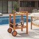 Rolling serving cart with teak oil finish, wine bottle holders, and rubber wheels, perfect for outdoor entertaining.