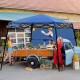 Blue 7 x 7 feet portable canopy tent in use at an outdoor market, providing shade for a gathering with fresh produce.