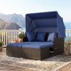 Outdoor patio rattan daybed with retractable canopy and navy cushions, perfect for relaxation by the poolside.