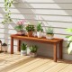 Backless outdoor wood bench with slatted seat, perfect for patio or garden, showcasing plants and flowers.