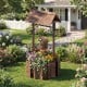 Outdoor wooden wishing well planter with burnt-like finish, featuring a bucket for smaller plants, perfect for garden.