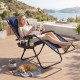 Portable zero gravity chair in navy with cup holder tray, adjustable pillow, and a woman relaxing outdoors.