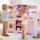 Children playing with a pink pretend play kitchen toy set featuring realistic sounds, lights, and various accessories.