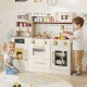 Beige pretend toy kitchen set featuring a close-up of the faucet, sink, and colorful food for imaginative playtime.