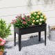 Elevated metal planter box with legs, featuring drainage holes, filled with colorful flowers for outdoor gardening.