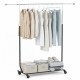 Extendable rolling clothes rack with hanging shirts and pants, featuring storage bins and suitcase for versatile use.