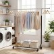 Extendable rolling clothes rack with hanging shirts, featuring a sturdy metal frame and storage bins for versatile use.