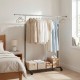 Extendable rolling clothes rack with hanging garments and storage bins, ideal for bedroom or laundry organization.