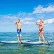 Two people paddle on a 10.5 feet inflatable stand-up paddle board in clear water, ideal for summer water activities.