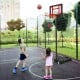 Children playing basketball with a portable hoop, adjustable height from 4.3FT to 8.2FT, ideal for outdoor fun.