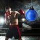 Boxer training with a 21-inch blue water punching bag featuring an adjustable chain, ideal for gym or outdoor use.