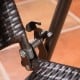 Close-up of the folding mechanism on a rattan bar chair with steel frame, featuring armrests and footrest for comfort.