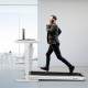 Folding treadmill in silver with remote control, used as an under-desk running machine for convenient exercise while.