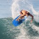 Surfer riding the Super Lightweight Bodyboard with EPS core, featuring a vibrant palm design for an exciting outdoor.