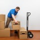 P-handle hand truck with foldable load plate, shown in use for moving boxes, ideal for warehouse and garage tasks.