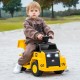 Child riding a yellow 6V electric Caterpillar construction vehicle with detachable dump bed and LED lights on a sandy.