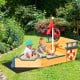 Kids playing in a wooden pirate boat sandbox with lifebuoy and rudder, perfect for outdoor fun and creativity.