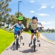 Two kids riding the 18 Feet Kids Bike with removable training wheels, featuring a white frame and adjustable components.
