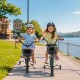 Two kids riding 12-inch bikes with training wheels along a scenic path, showcasing adjustable seats and sturdy frames.