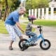 Child riding a blue 12-inch kids bike with removable training wheels, designed for ages 3-4, in a park setting.