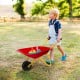 Red metal wheelbarrow for kids with seamless steel tray and rubber handles, perfect for outdoor yard play and.