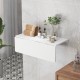 Wall-mounted drop-leaf table in sleek white finish, perfect for small spaces, used as a dining or storage surface.